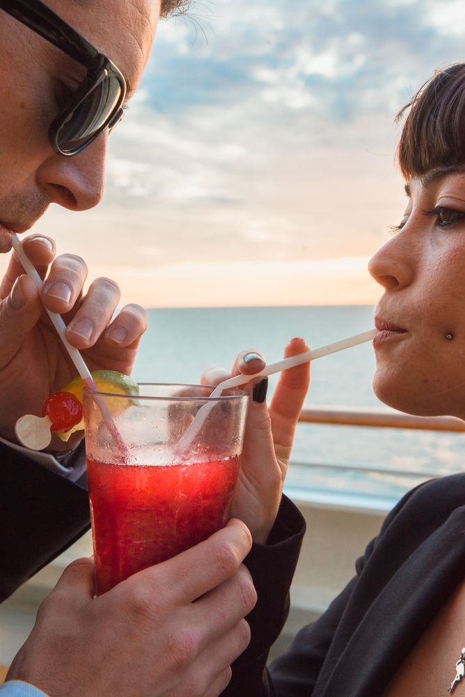 Young man and woman drinking juice from one glass