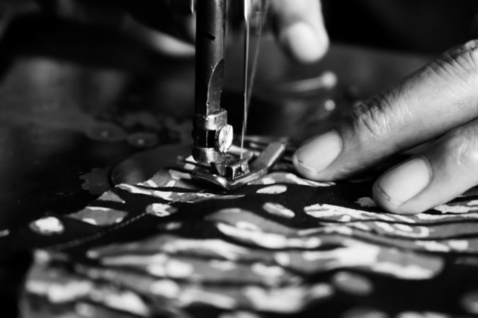 Close up of person's hands using sewing machine working on batik Indonesian fabric