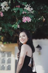 Side view of woman in dark dress standing under floral tree