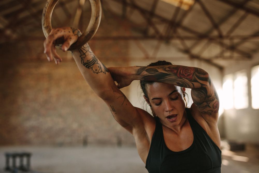 Woman exercising with gymnastic rings in gym – Jacob Lund