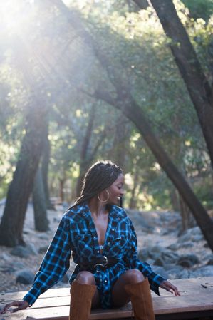 Fashionable woman sitting on bench in the woods