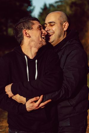 Smiling men hugging on path in park
