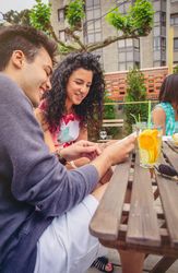 Friends reviewing book outside with cocktails