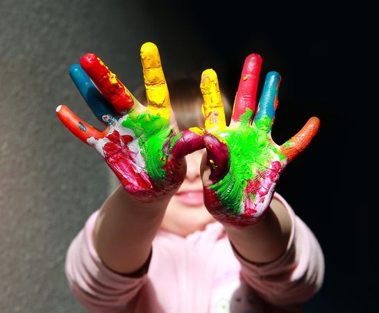 Young child holding painted hands up to the camera