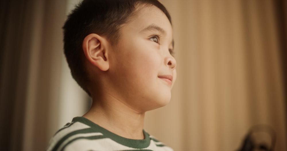 Portrait of a Little Cute Asian Boy Looking Through a Window and Smiling.