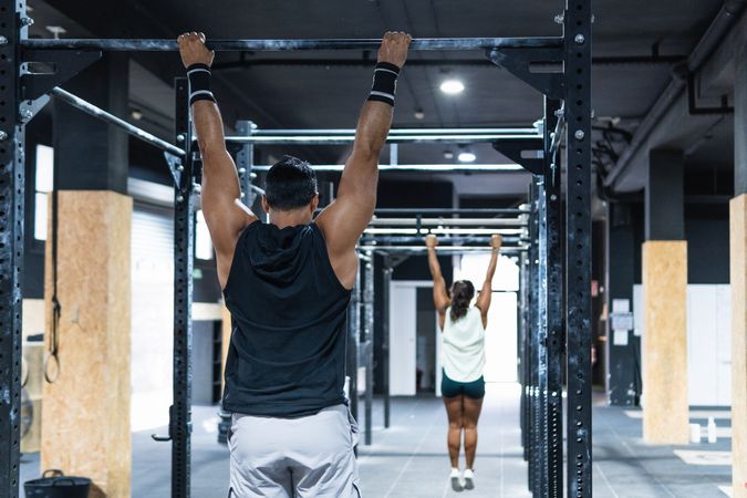 Faceless sportive couple hanging on crossbars