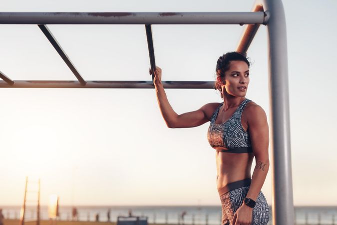 Portrait of muscular  woman standing by monkey bar exercise equipment outdoors