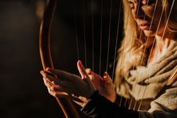 Sensual female musician playing lyre in garden