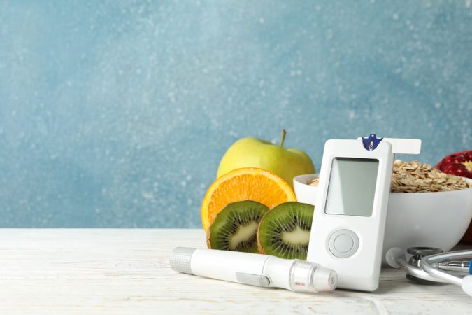 Blood glucose meter and diabetic food on wooden table