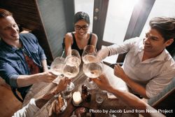 Top view of young men and women sitting at a restaurant and toasting wine bYOEN5