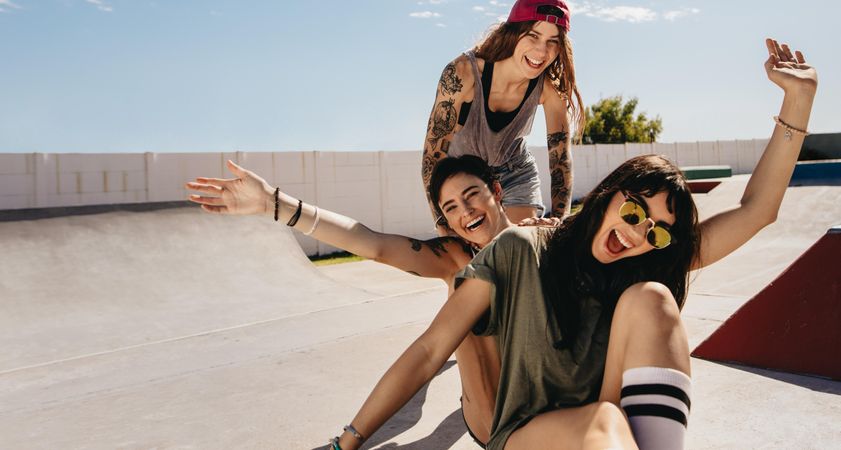 Three women being silly sitting on skateboards laughing and having fun