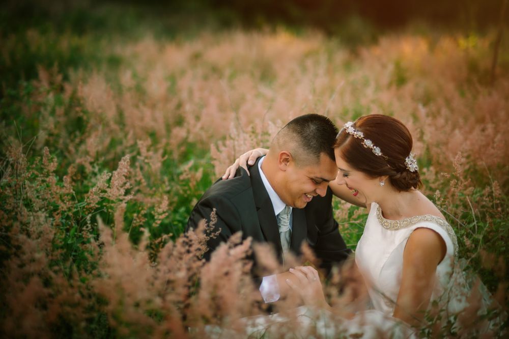 Smiling groom and bride hugging and kissing in park