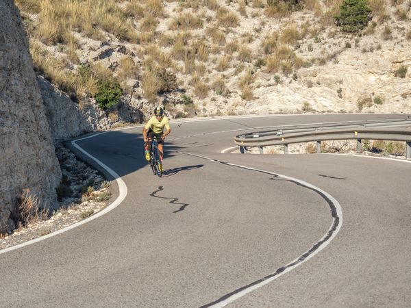healthy man riding a bicycle on a mountain road in a sunny day