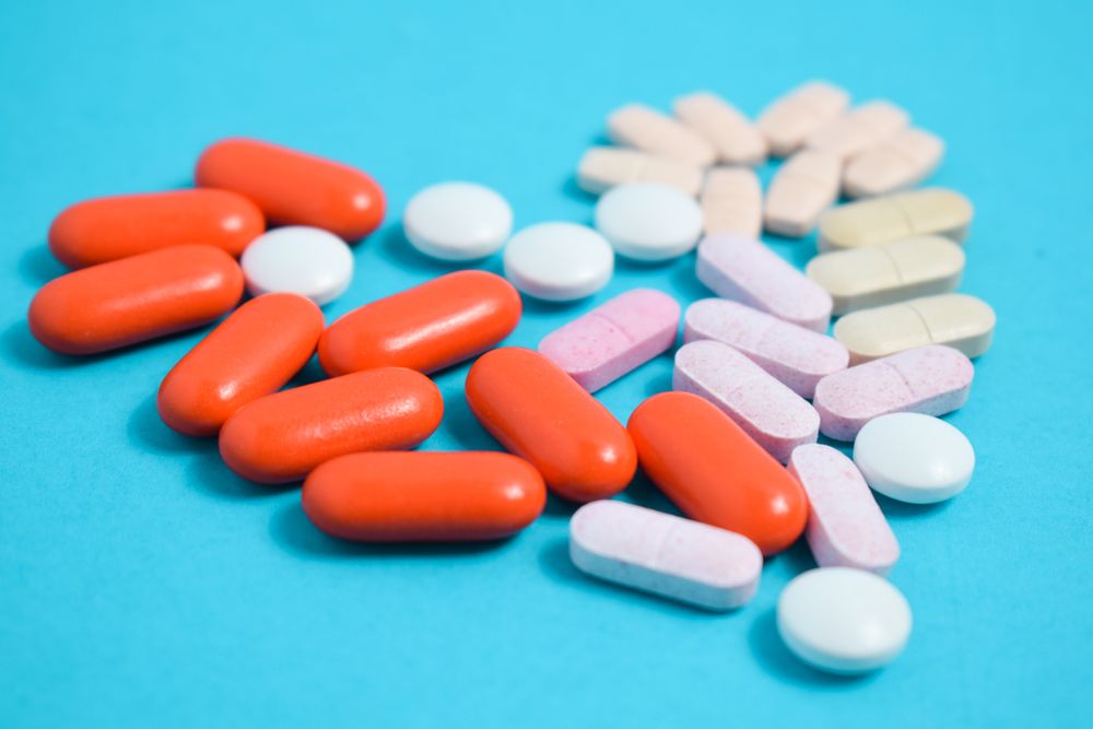 Variety of pIlls in heart shape on blue table