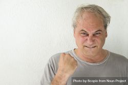 Portrait of excited middle aged man in gray shirt against light background bGXja0