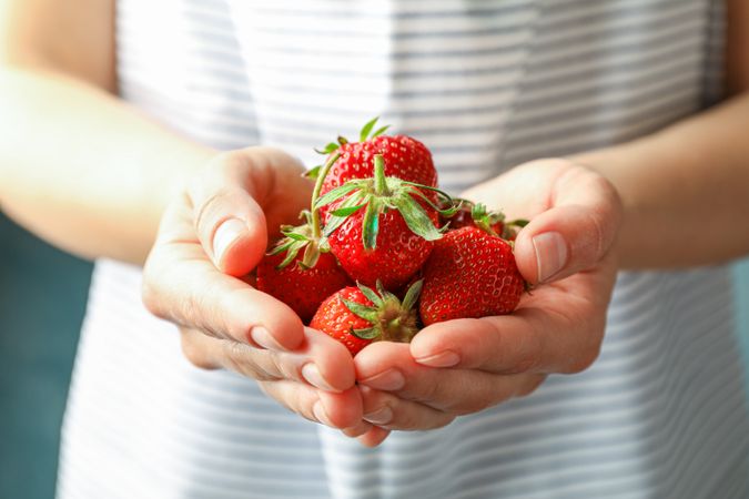 Young woman holding fresh strawberries, space for text and closeup. Summer sweet fruits and berries