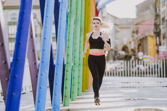 Woman with earphones running on street