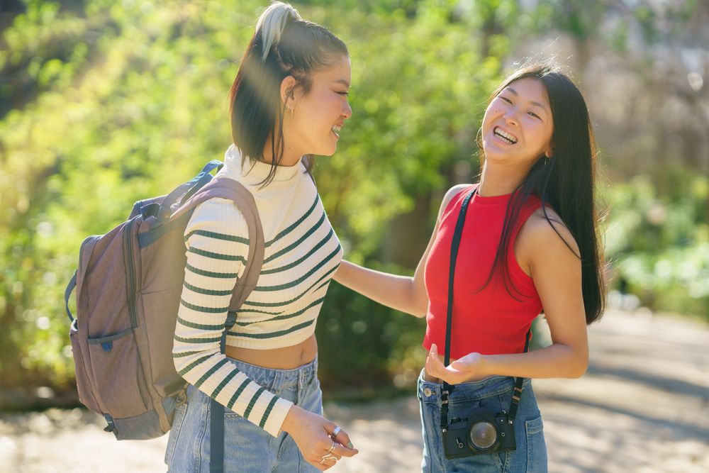 Two women chatting and standing on walking path in park
