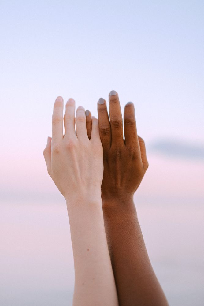 Two hands touching under sunset sky
