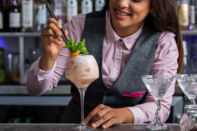 Bartender adding mint leaves to a cocktail