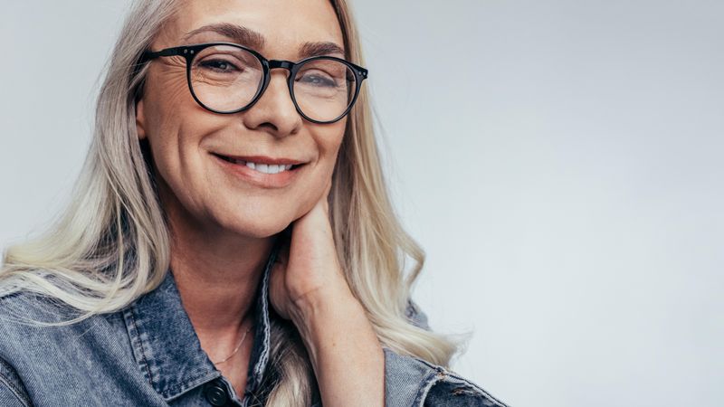 Close up of mature woman wearing glasses against grey background