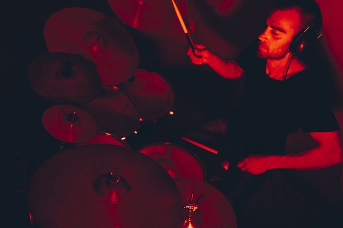 Man with drumsticks playing on drums in redness