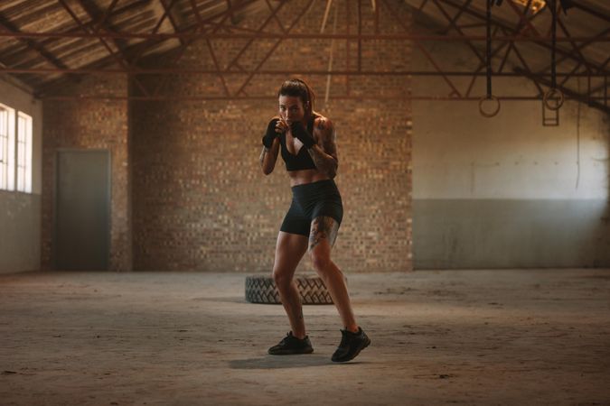 Woman doing shadow boxing exercise in empty factory shade
