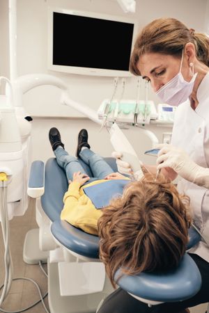 Woman doing dental scanning to preteen boy