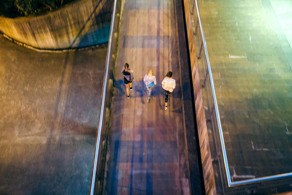 Looking down at group of female runners training together over city runway at night