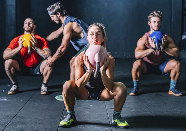 Athletic friends exercising with weight in gym