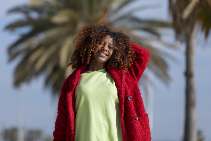 Happy female with hand to her curly hair on sunny day