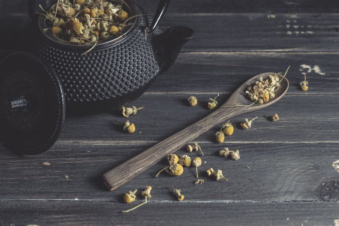 Spoonful of dried chamomile on wooden table