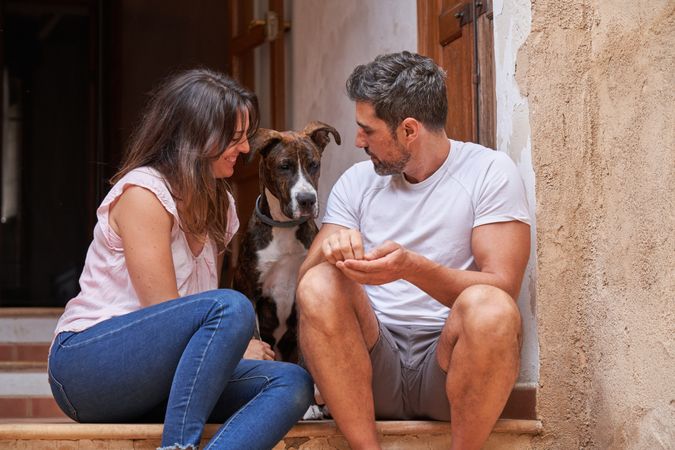 Happy couple with dog sitting on porch