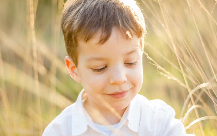 Kid in field playing with spikes at summer sunset