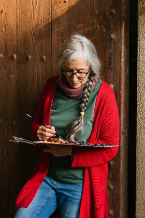 Cheerful painter with paint palette looking at camera