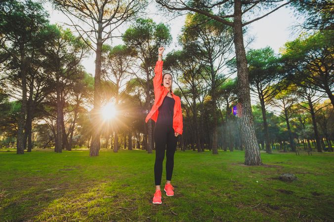 Excited sportswoman with arms raised in park