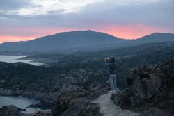 Male taking photo on cliff at sunset