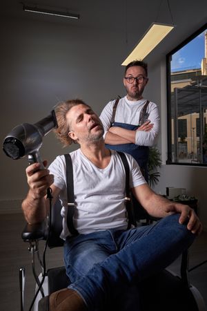 Relaxed brutal man drying hair in barbershop