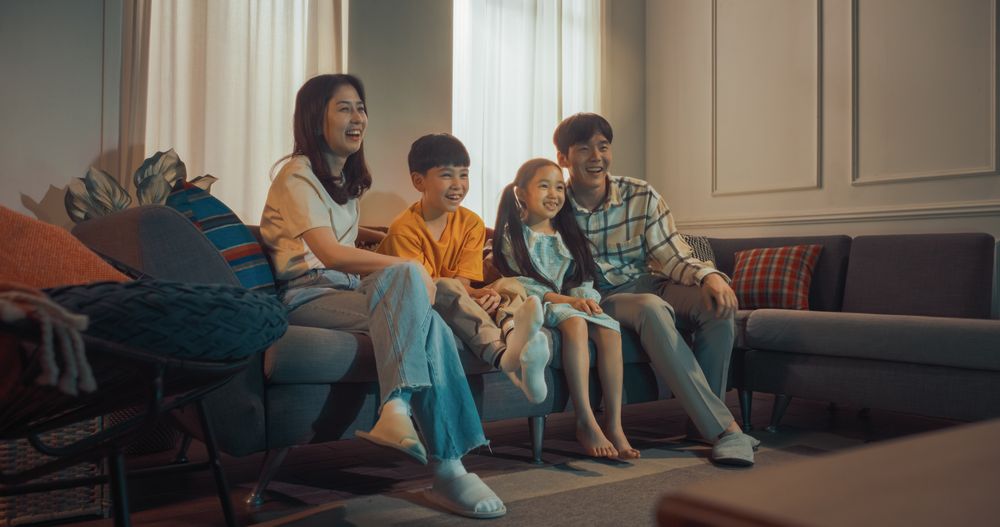 Siblings Having Fun With Parents In Cozy Living Room.