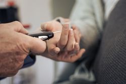 Doctor performing a blood sugar test on a patient's finger.