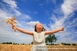 Happy girl with outstretched arms in a wheat field bYDYG4