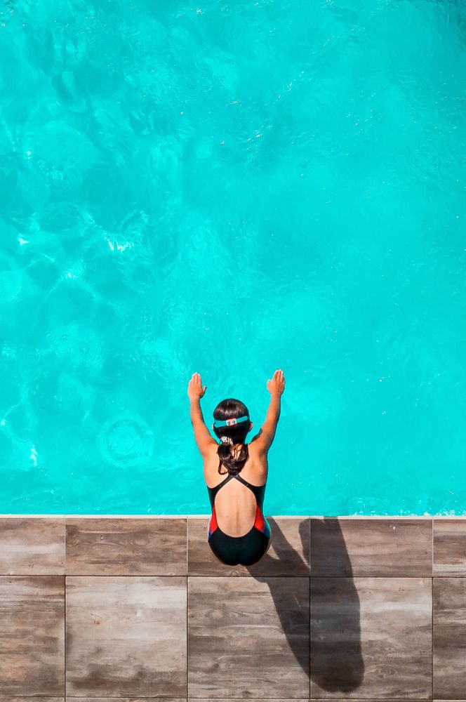 Child. The swimmer girl is about to jump into the water.