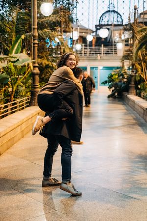Man carrying happy girlfriend on back