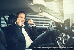 Happy man making a celebratory fist while talking on his cell phone in a vehicle 5k1PAb