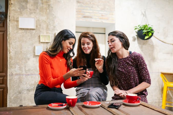 Three women sharing something on phone screen