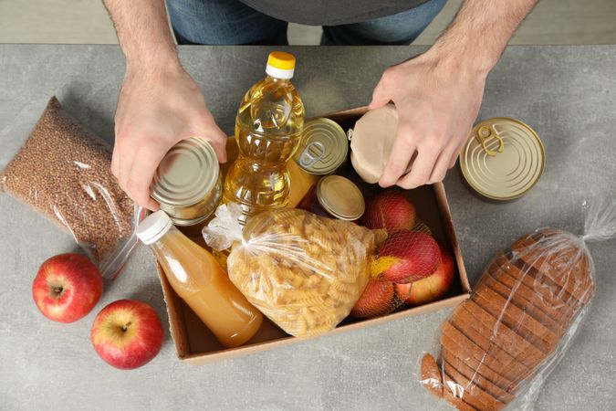 Young man puts groceries in donation box. Volunteer
