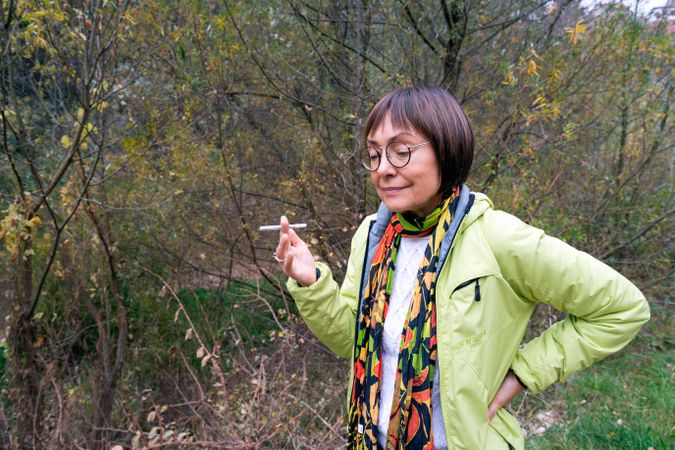 Woman in bright clothes having a smoke break in the forest