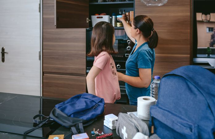 Mother preparing emergency backpack with her daughter