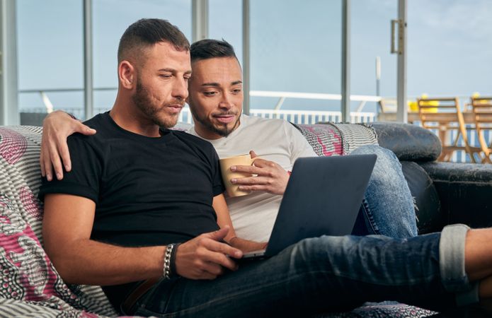 Happy gay couple using laptop at home