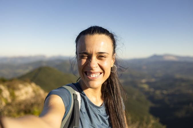A young woman smiles at the sun from the top of a mountain near Pgasarri in the Basque Country